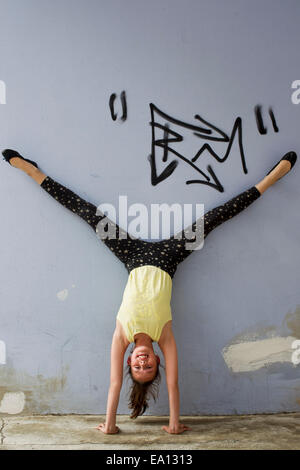 Teenage girl doing handstand contre mur Banque D'Images