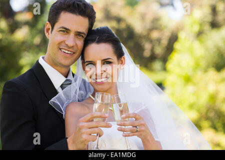 Newlywed toasting champagne flutes at park Banque D'Images