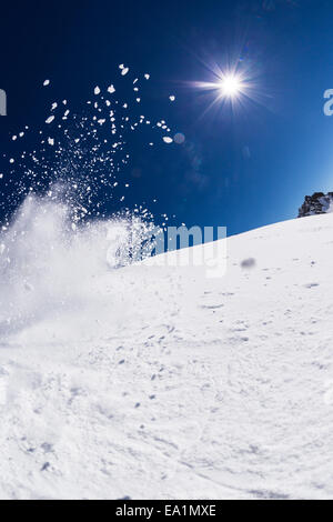 Motion shot de poudreuse avec lever du soleil et ciel bleu sur l'arrière-plan Banque D'Images