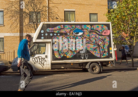 Un homme passe devant un van avec le tag graffiti et une peinture psychédélique dans les rues de Camden Town. Banque D'Images