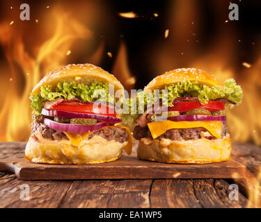 Fresh home-made hamburgers servis sur des planches. Les flammes de feu autour de Banque D'Images