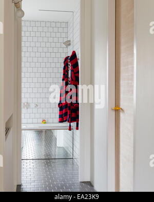 Vue vers le bas couloir à une salle de bains privative avec carreaux de mur blanc Banque D'Images