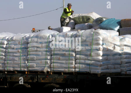 Le 5 novembre 2014 - Rafah, bande de Gaza, territoire palestinien - un travailleur palestinien supprime le cache en plastique sur un sommet d'un camion chargé de fournitures qui sont entrés dans la bande de Gaza d'Israël par le terminal de Kerem Shalom à Rafah dans le sud de la bande de Gaza le 5 novembre 2014. Envoyé spécial de la paix de l'ONU Robert Serry a annoncé le 4 novembre que le mécanisme de reconstruction temporaire pour le territoire palestinien a commencé ses activités, sous les auspices du nouveau gouvernement palestinien d'union nationale, notant l'urgence dans la fourniture de ciment et autres matériaux à des dizaines de milliers de maisons endommagées Banque D'Images