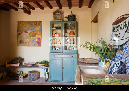 Commode bleu plein de vaisselle aux couleurs vives et de bidons en chambre rustique avec des illustrations et vintage enamel sign Banque D'Images