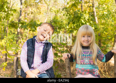 Heureux les petits enfants blancs à l'automne Fashion Outfit Visiter les bois pendant la saison d'automne. Capturé avec arbres verts à la Backg Banque D'Images