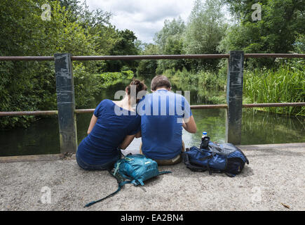 Couple assis sur le pont traversant la rivière Itchen dans le Hampshire, England, UK Banque D'Images