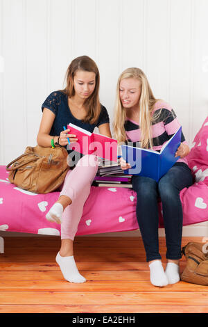 Deux teengirls assis sur le lit faisant devoirs ensemble Banque D'Images