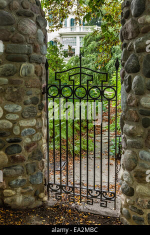 Porte en acier avec des poteaux en pierre menant au jardin. Banque D'Images