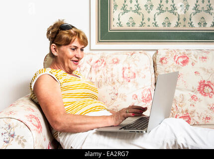 Happy young woman using laptop at home Banque D'Images