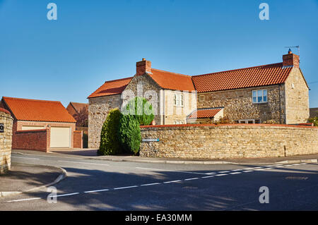 Maison construite en pierre moderne face au soleil contre un ciel bleu clair, dans village Langtoft, Lincolnshire, près de Peterborough, England, UK. Banque D'Images