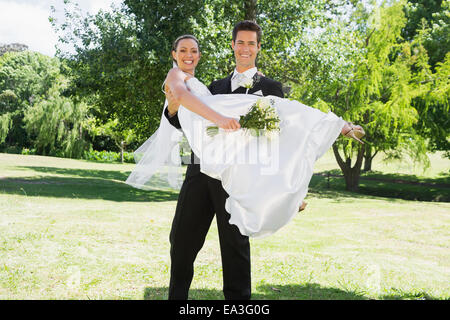 Marié jeune mariée dans les bras de levage au jardin Banque D'Images