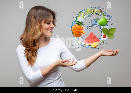 Femme souriante avec des fruits et les éclaboussures d'eau Banque D'Images