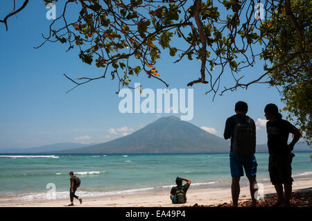 Personnes ayant du temps de loisirs sur une plage face au détroit de Boleng et au mont Boleng (île d'Adonara); photographiées à l'île de Lembata, Indonésie. Banque D'Images