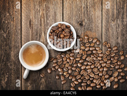 Tho petites tasses à café blanc pleins d'espresso et de fèves torréfiées, vue du dessus sur la vieille table en bois Banque D'Images