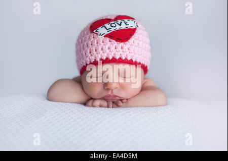 Portrait d'un bébé âgé de sept jours en bonneterie fille portant un bonnet d 'Amour'. Cute tourné à utiliser pour la Saint-Valentin. Banque D'Images