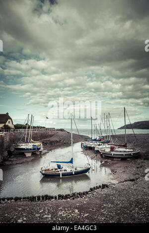 Bateaux à voile reposent délicatement sur le sable, la boue et les rochers à marée basse dans le petit port de Porlock Weir, Somerset . Banque D'Images