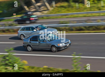 Deux voitures accélérant le long d'une autoroute, l'un dépassant les autres. Flou de mouvement utilisée pour donner une idée de la vitesse. Banque D'Images