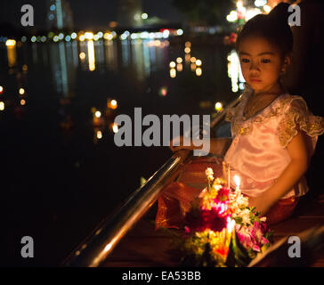 Parc Benjakiti, Bangkok, Thaïlande, le 6 novembre 2014. Une jeune fille thaïe montres sur comme son krathong décorées (panier) est prêt à flotter sur le lac du parc Benjakiti pour célébrer l'Assemblée Loi Krathong festival. Loi Krathong est un festival annuel célébré en Thaïlande pour rendre grâce à la Déesse de l'eau, Phra Mae Khongkha. Credit : Alison Teale/Alamy Live News Banque D'Images