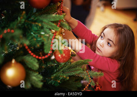 Cute little girl decorating Christmas Tree Banque D'Images