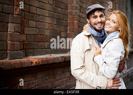 Portrait of smiling couple dans l'élégant quartier de trench-coats à la caméra à l'extérieur Banque D'Images