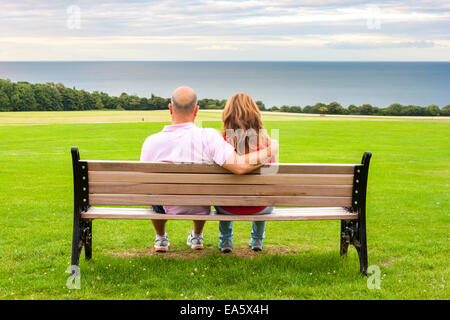 Vue arrière du moyen age couple assis sur un banc face à la mer Banque D'Images