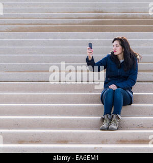 Femme assise sur un pas en prenant un selfies Banque D'Images