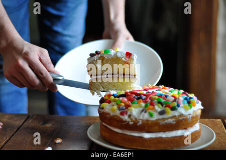 L'homme en découpant une tranche de gâteau d'anniversaire Banque D'Images