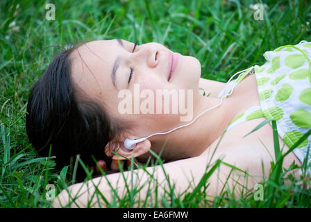 Girl lying on grass à écouter de la musique Banque D'Images