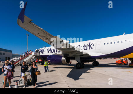 Les vacanciers de marcher sous l'aile d'un Monarch Airlines Airbus A321 avion à l'aéroport de Palma de Majorque Banque D'Images