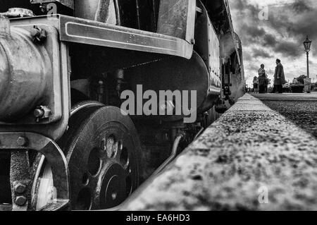 Vue au niveau de la plate-forme de l'avant d'une Bulleid Pacifique lumière loco vapeur debout dans une plate-forme en noir et blanc Banque D'Images