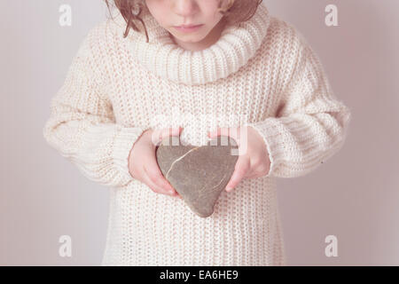 Girl holding heart shaped stone Banque D'Images