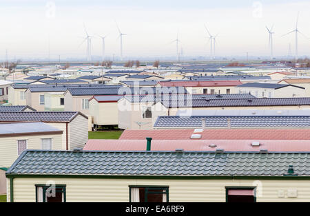 L'ombre pastel caravanes statiques dans un parc de vacances à Camber Sands, East Sussex, England, UK - wind farm in background Banque D'Images