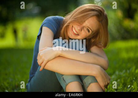 Belle jeune fille rousse sitting on grass Banque D'Images