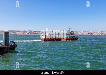 Un ferry de Lisbonne, connu comme un Cacilheiro s'écarte de l'aérogare pour connecter la ville d'Almada au vu de Lisbonne à l'horizon. Banque D'Images