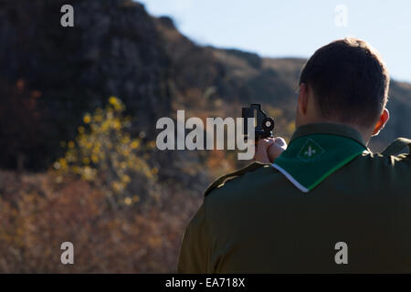 Navigation scouts dans le désert de la lecture sur un pic de montagne avec son compas magnétique afin d'établir son emplacement, vue de derrière. Banque D'Images