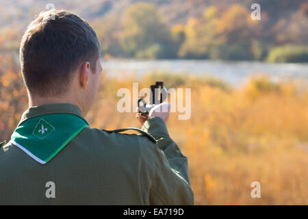 Vue de derrière sur l'épaule d'un scout de la lecture avec un compas magnétique pour naviguer dans son chemin à travers le désert. Banque D'Images