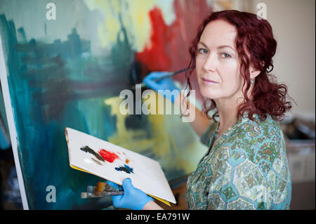 Portrait of middle-aged woman holding palette et peinture sur toile Banque D'Images