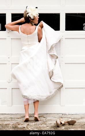 Vue arrière de mid-adult woman standing on faufille peeking through fenêtre garage Banque D'Images