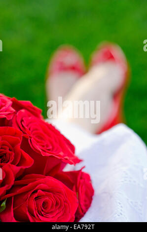 Close-up shot de bouquet de roses rouges sur les genoux de la mariée Banque D'Images
