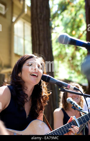 Jeune femme chanter et jouer en plein air de guitare Banque D'Images