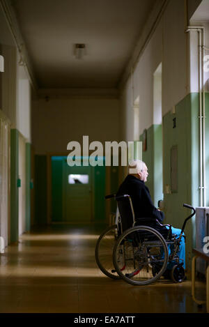 Vieil homme sur un fauteuil roulant à la fenêtre d'un seul sur un long couloir Banque D'Images