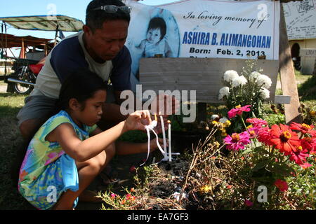 Palo, Philippines. Nov 8, 2014. Un homme vient en aide à une jeune fille s'allumer une bougie pour une famille memberwho est mort il y a un an exactement tel à San Joaquin, Palo, Leyte. San Joaquin à Palo, Leyte est l'un de la région la plus durement touchée par le typhon Haiyan, il y a un an. Avec les ondes de tempête aurait été d'atteindre 20 pieds, des centaines de personnes sont mortes au cours de la première heure de la tempête. Crédit : J Gerard Seguia/Pacific Press/Alamy Live News Banque D'Images