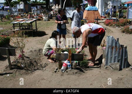 Palo, Philippines. Nov 8, 2014. Une famille paie leur respect à un membre de la famille qui ont péri pendant le typhon Haiyan's onslaught il y a un an à San Joaquin, Palo, Leyte. San Joaquin à Palo, Leyte est l'un de la région la plus durement touchée par le typhon Haiyan, il y a un an. Avec les ondes de tempête aurait été d'atteindre 20 pieds, des centaines de personnes sont mortes au cours de la première heure de la tempête. Crédit : J Gerard Seguia/Pacific Press/Alamy Live News Banque D'Images