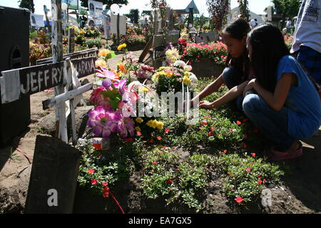 Palo, Philippines. Nov 8, 2014. Deux jeunes filles allument une bougie sur la tombe d'un membre de la famille dans la région de San Joaquin, Palo, Leyte. San Joaquin à Palo, Leyte est l'un de la région la plus durement touchée par le typhon Haiyan, il y a un an. Avec les ondes de tempête aurait été d'atteindre 20 pieds, des centaines de personnes sont mortes au cours de la première heure de la tempête. Crédit : J Gerard Seguia/Pacific Press/Alamy Live News Banque D'Images