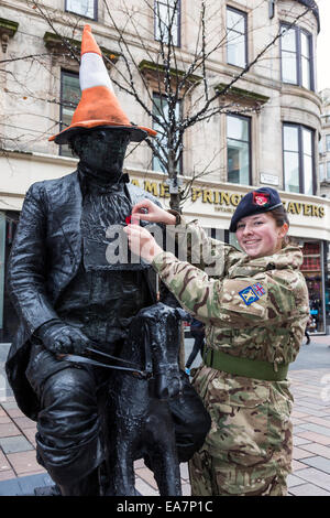 Glasgow, Ecosse, Royaume-Uni. Nov 8, 2014. Abby Malcolm, 16 ans, de Maryhill, Glasgow, Ecosse, un membre de la Gendarmerie royale, la collecte pour les cadets du signal à l'Écosse Dans Buchanan Street, Glasgow. Ici, il est épinglé un coquelicot sur Kevin Powell, de Cheshire, un artiste de rue et "statue vivante" qui est en costume imitant la statue de la célèbre statue du Général Arthur Wellesley, 1er duc de Wellington, à Royal Exchange Square, vu iconically avec un cône de stationnement sur son siège. Credit : Findlay/Alamy Live News Banque D'Images