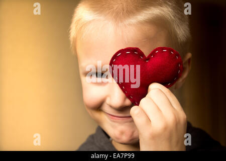 Happy cute child (enfant, garçon) avec coeur rouge fait main. La Saint-Valentin et l'amour familial concept. Close up portrait of horizontal. Banque D'Images