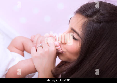 Closeup portrait of cute mother kissing feet pacifiques de son petit bébé, heureux jeune famille, d'amour et de la protection des enfants Banque D'Images