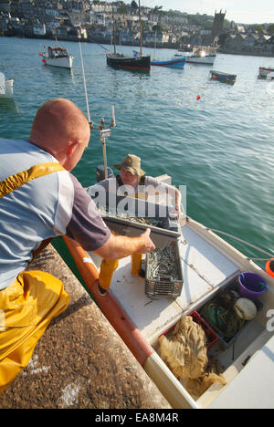 Les pêcheurs de cirés jaune sable de captures d'anguilles dans les boîtes de poisson sur le quai des bateaux de pêche sur la jetée de Smeaton'S St Ives Har Banque D'Images