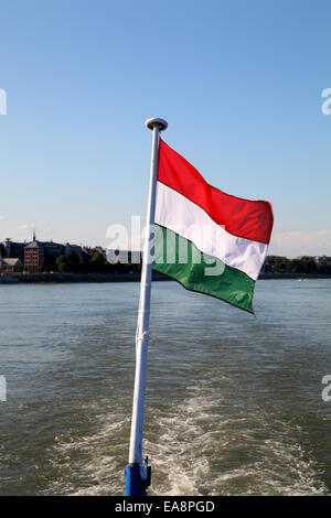 Drapeau hongrois contre un ciel bleu piloté à partir de l'arrière du bateau de croisière sur le Danube, près de Budapest Hongrie Banque D'Images