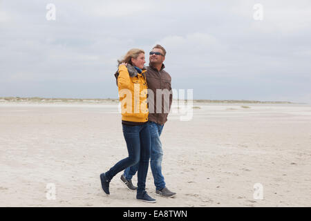 Un jeune couple promenades sur la plage de sable fin à l'automne Banque D'Images